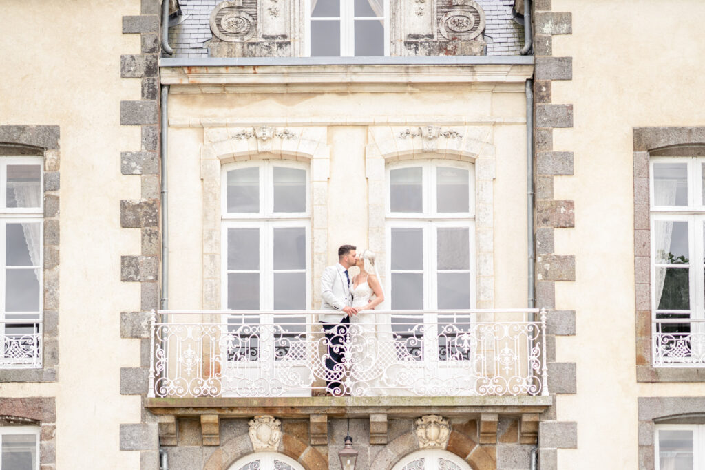 Bride and groom sharing a kiss on the front balcony at Chateau du Grand Val  in Brittany, France. 