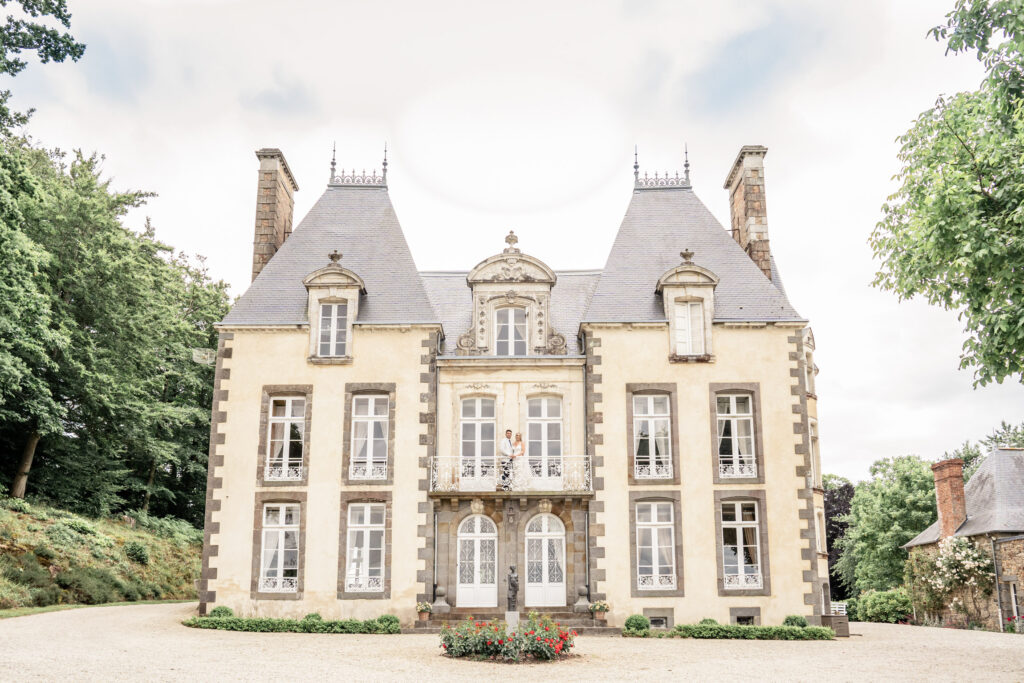 Bride and groom posing together on the front balcony at Chateau du Grand Val wedding venue in Brittany, France. 