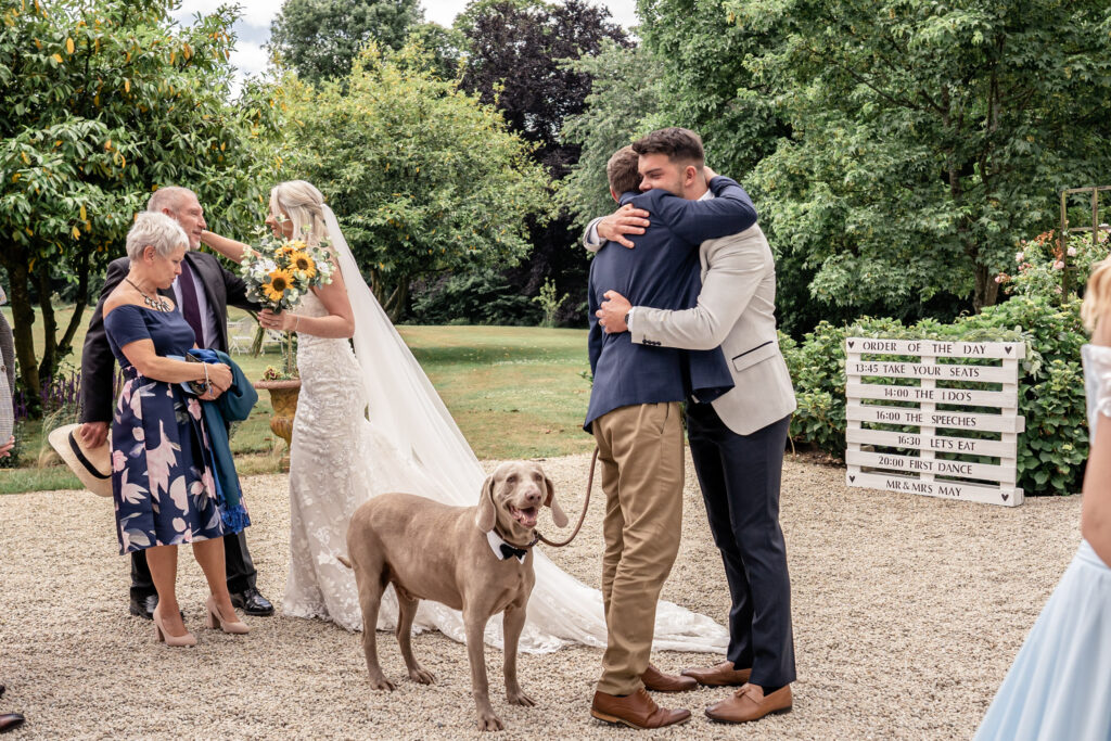 A bride and groom hugging their guests with their dog at their wedding