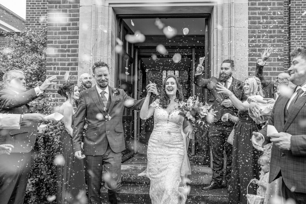 A bride and groom stepping out of wedding venue for the first time as husband and wife